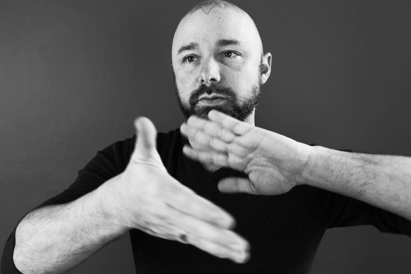 Portrait of Miah Jeffra in a black and white photo with his hands in movement in front of his chest