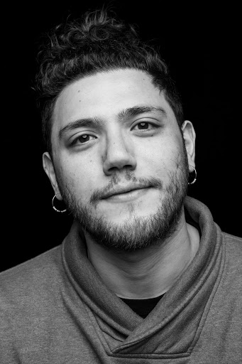 Black and white portrait of Dujie Tahat wearing two earrings in front of a dark background