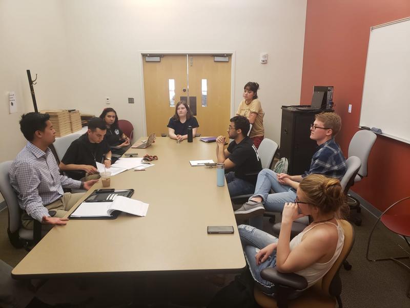 Club members sit around a large wood table during a meeting.