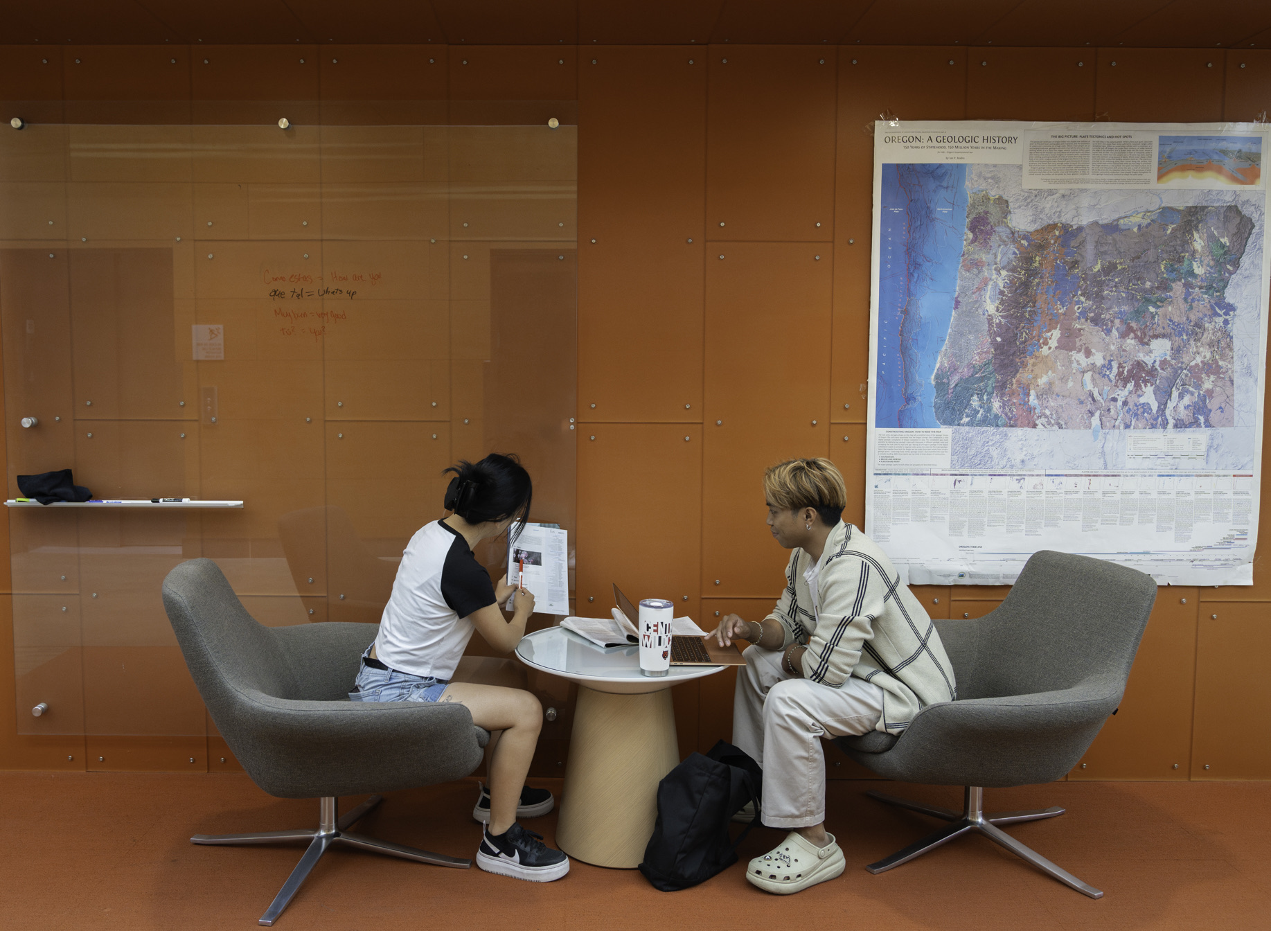 Two students sitting outside the classroom having a conversation