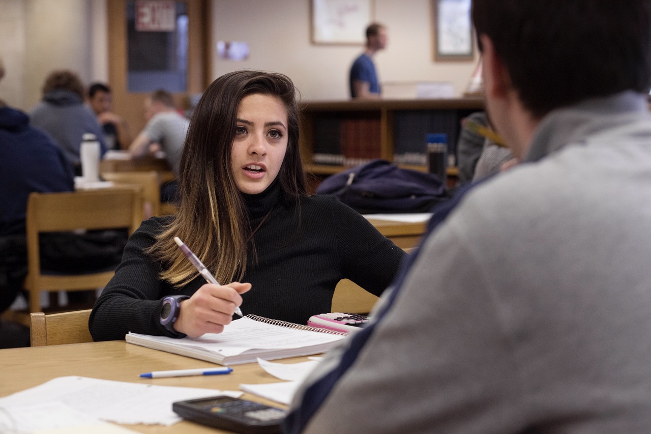 Student having a conversation with another student across the table.