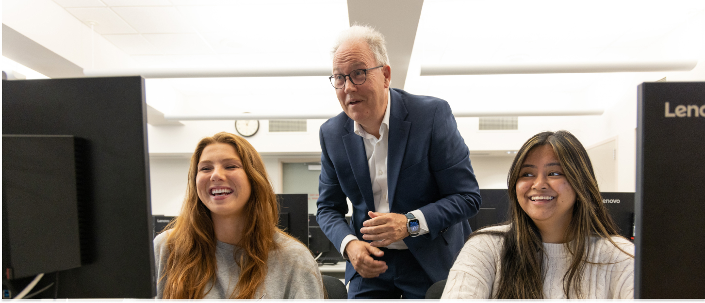 Professor working with students on computers.