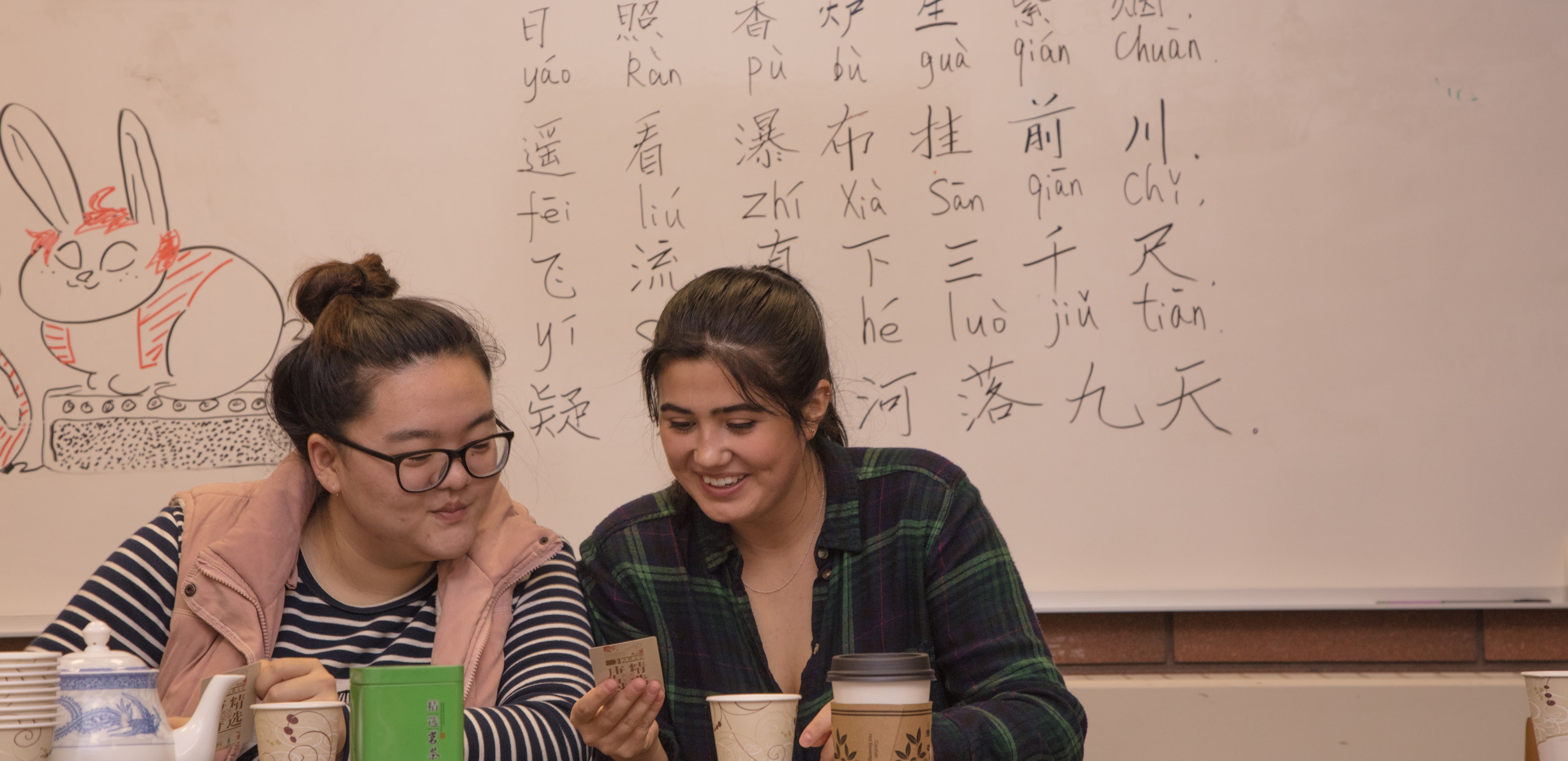 Two students sitting in front of a whiteboard full of Chinese characters