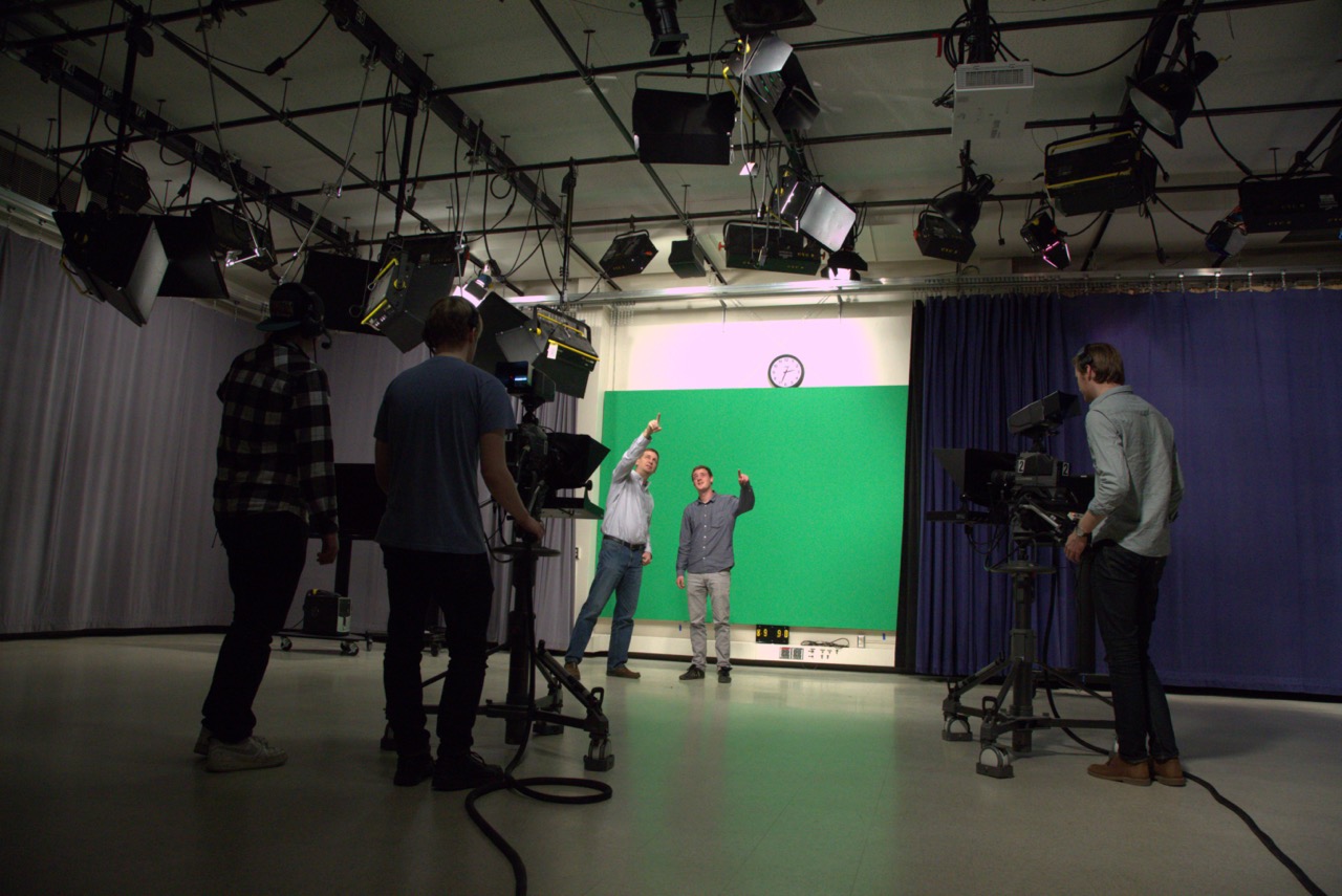 Student working with faculty while being filmed on a green screen