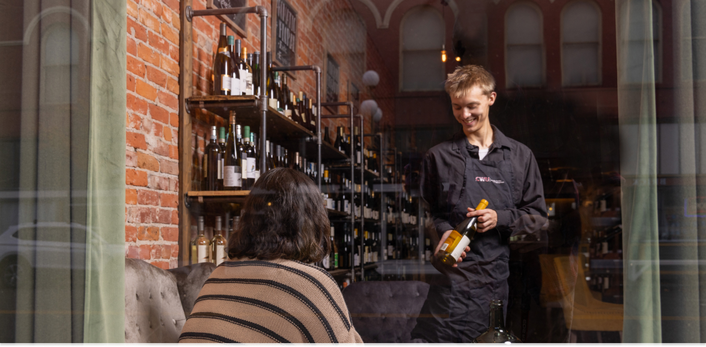 Photo outside of a restaurant showing a student working with a client in the hospitality program.
