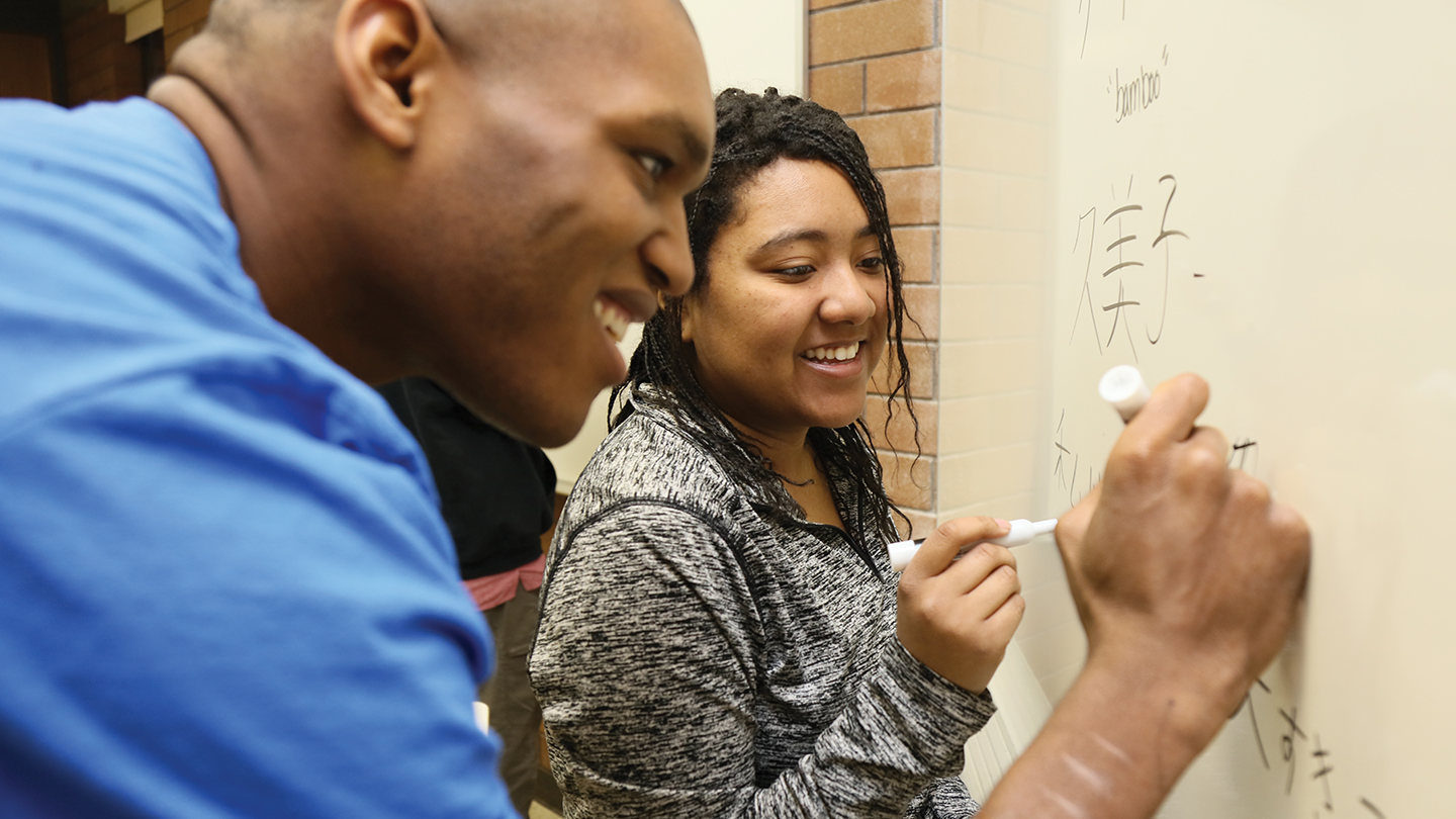 Two students writing in Japanese on the whiteboard