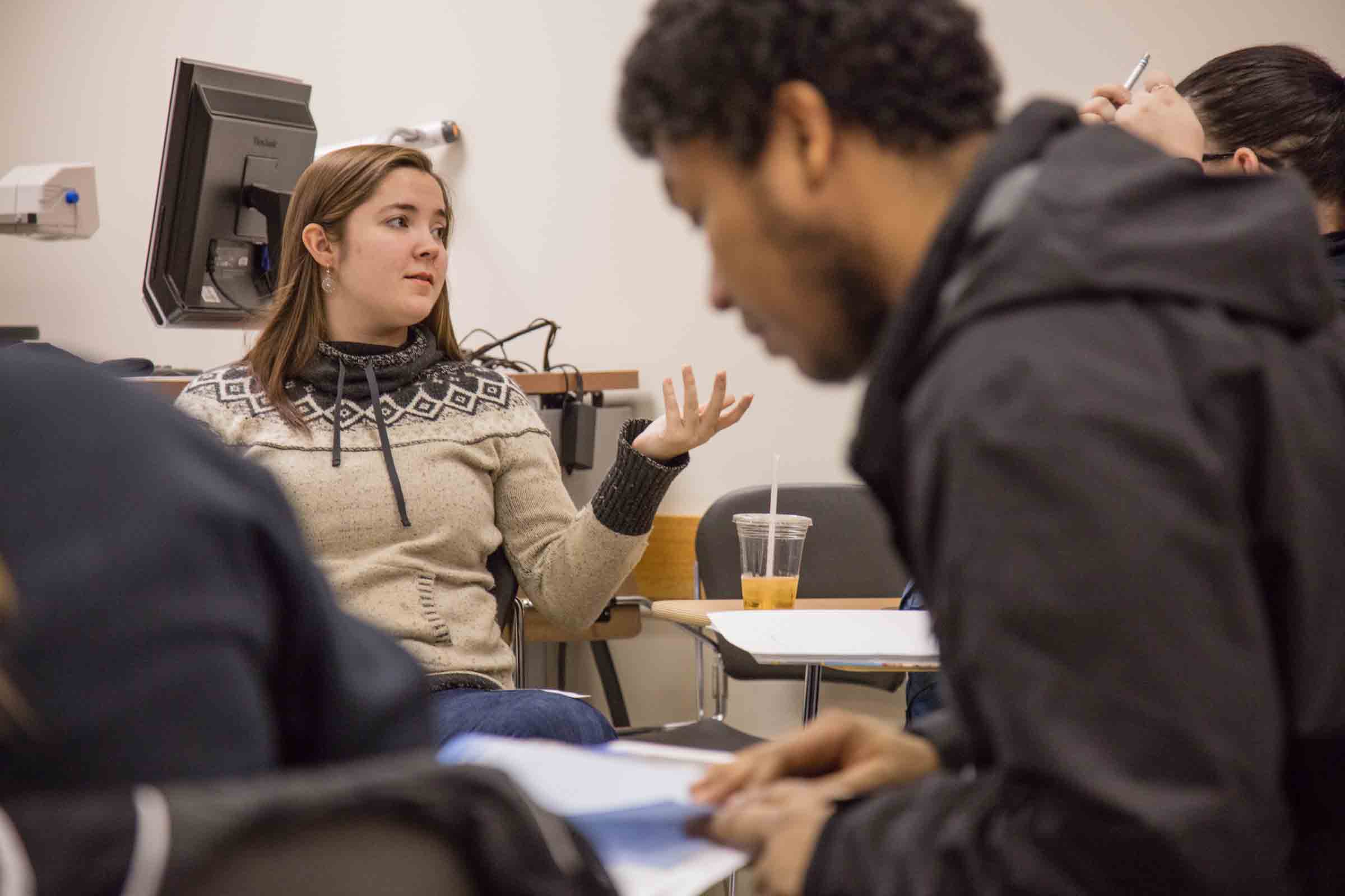 student talking to her peers in a classroom