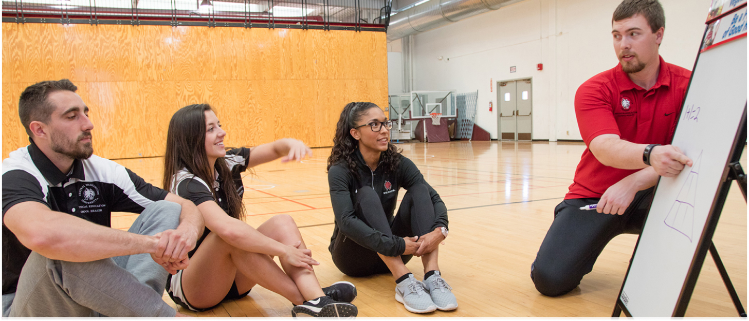 Professor walking through something on a whiteboard in the middle of a gym.