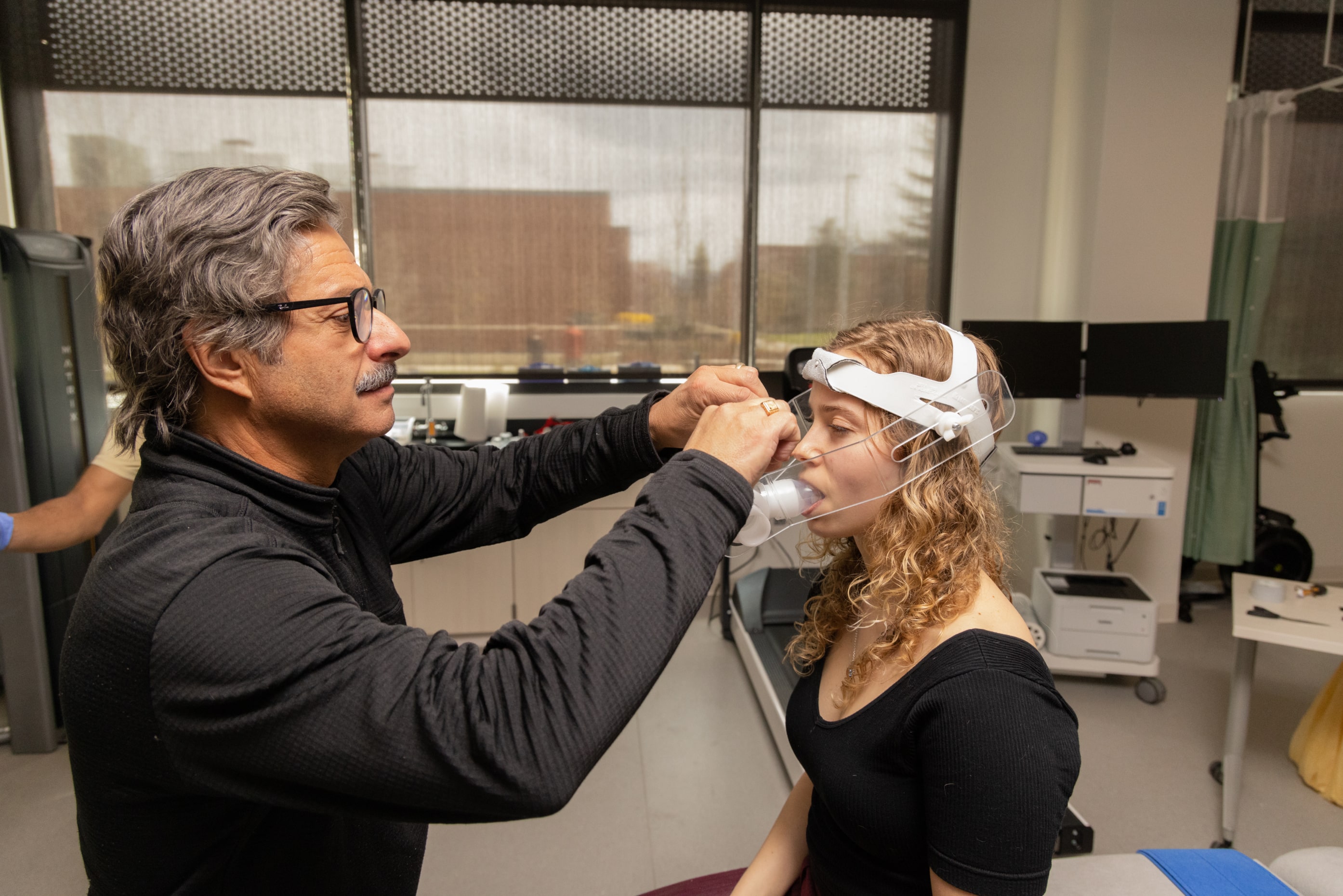 Professor measuring the lung capacity of a student.