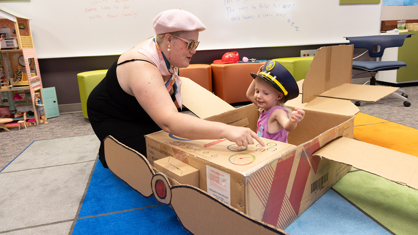 Student working with children during practicum experience, both wearing fun hats