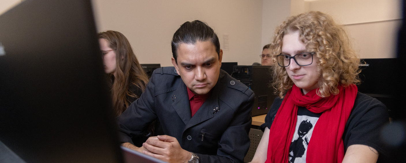 Student working with a professor in a computer lab.