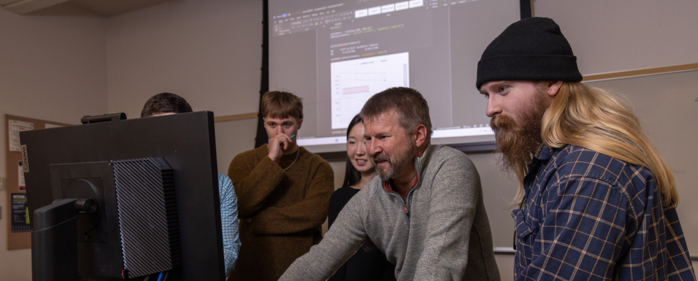 Students working on a computer with professor.