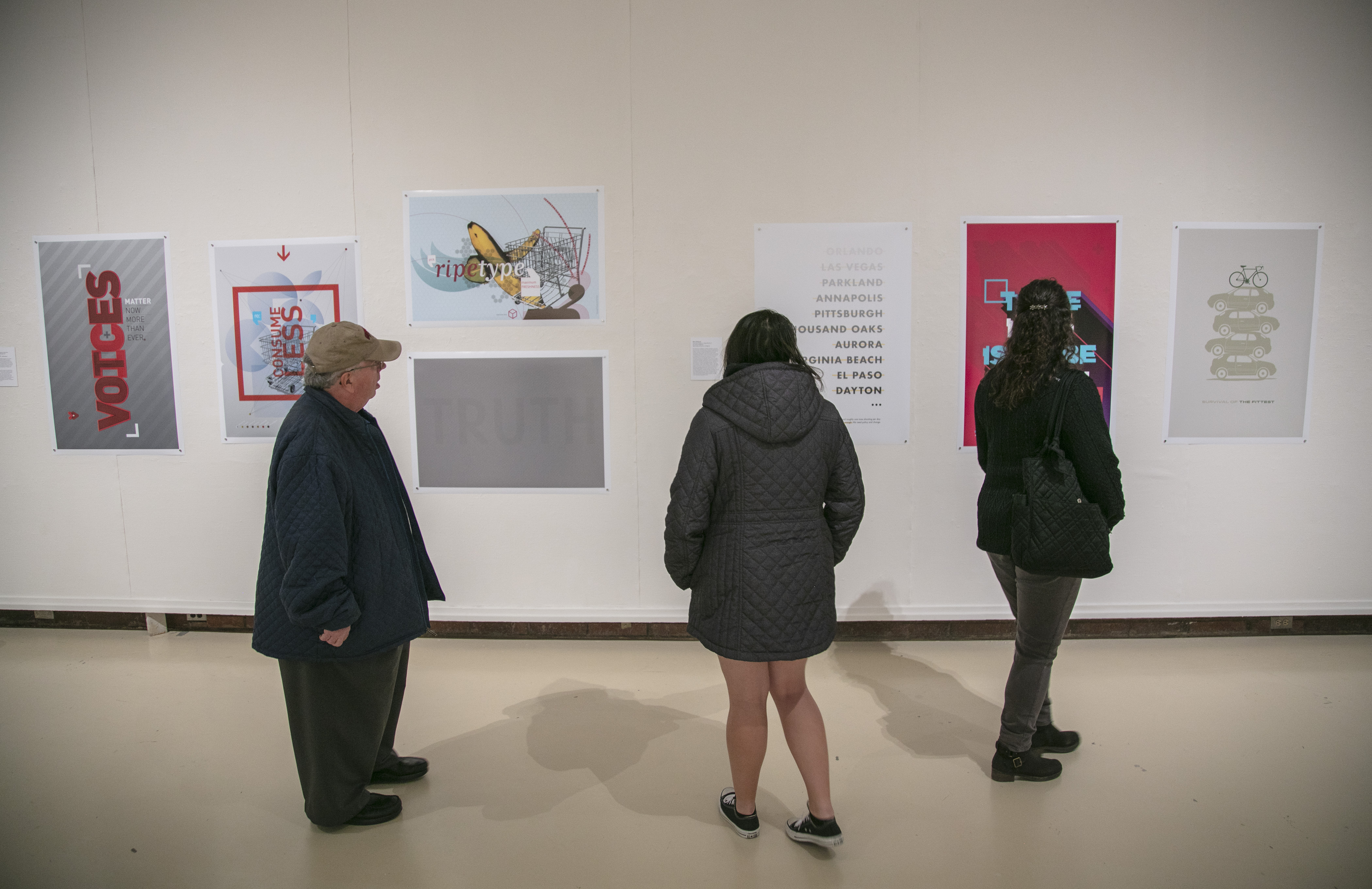 students looking at a poster show in the gallery on campus