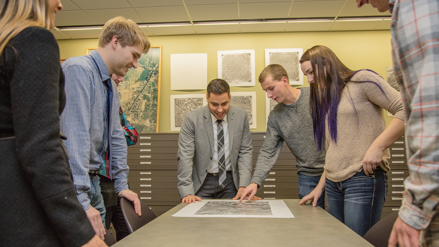 Studens and a professor looking at a map.
