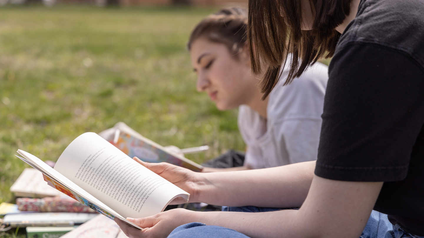 Two students reading on the campus lawn