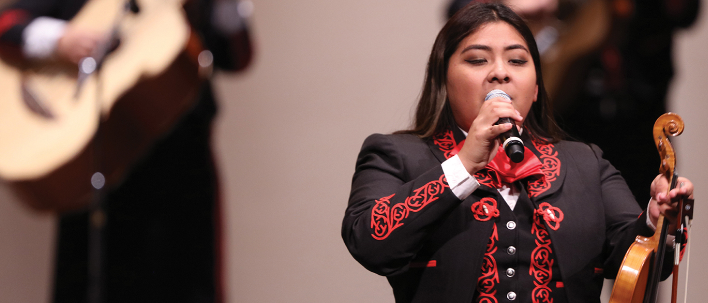 mariachi singing with a guitar playing in the back