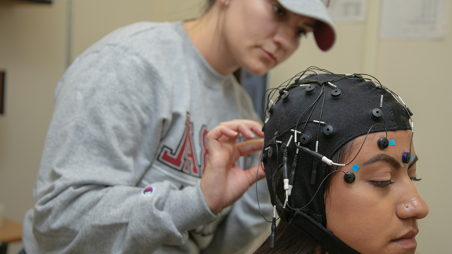 Student adjusting a piece of equipment on another student's head.