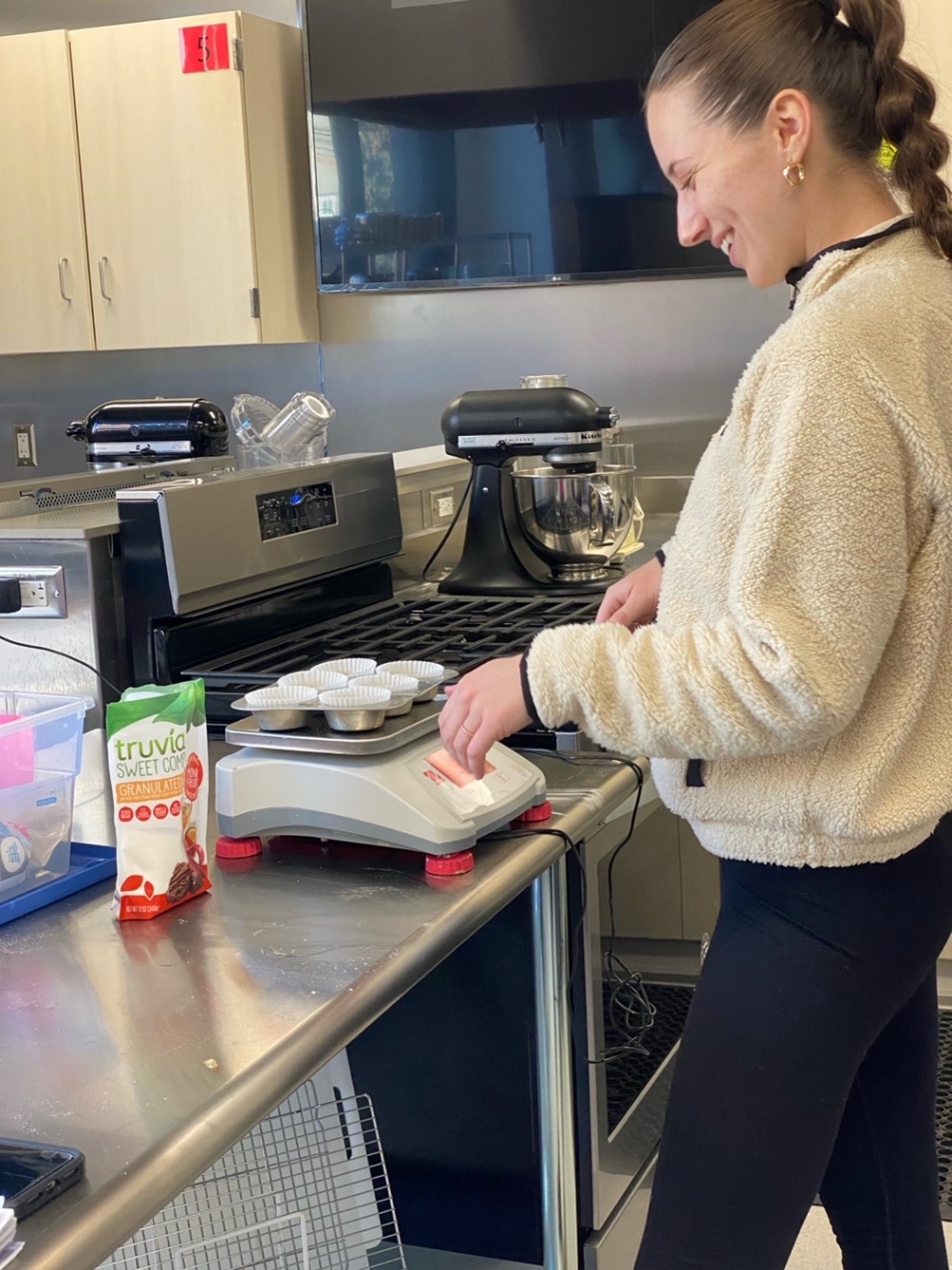 A woman smiling at a food scale 