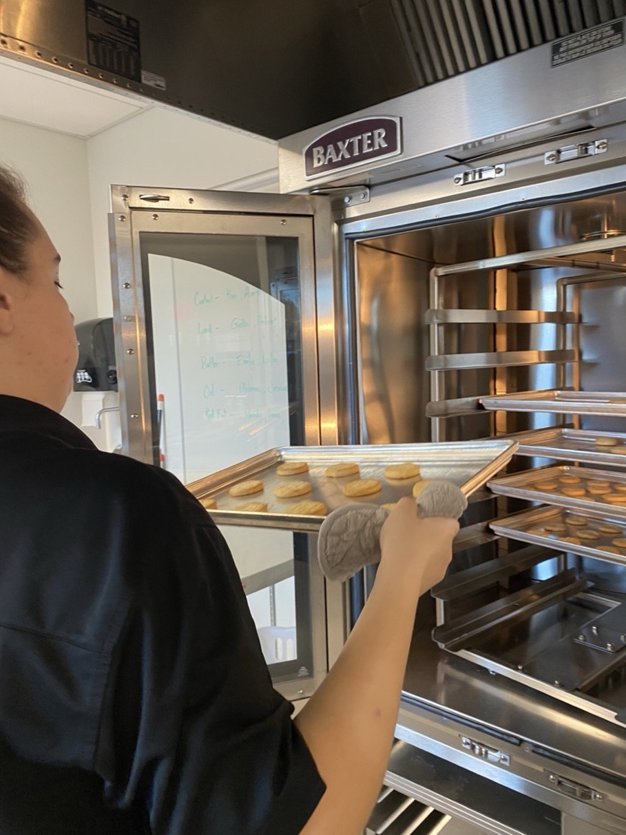 a student putting cookies into an oven