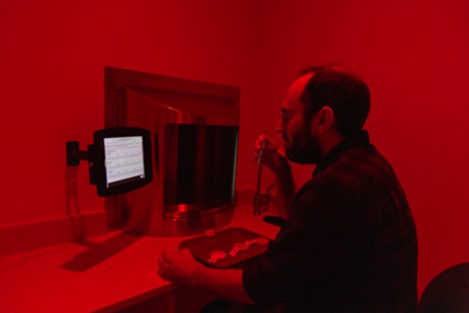 A man trying food in a dark room with red glowing in the background