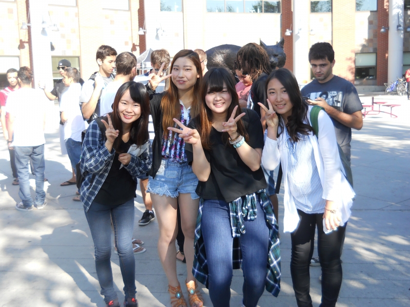 Multiple ESL students smiling at the camera outside.