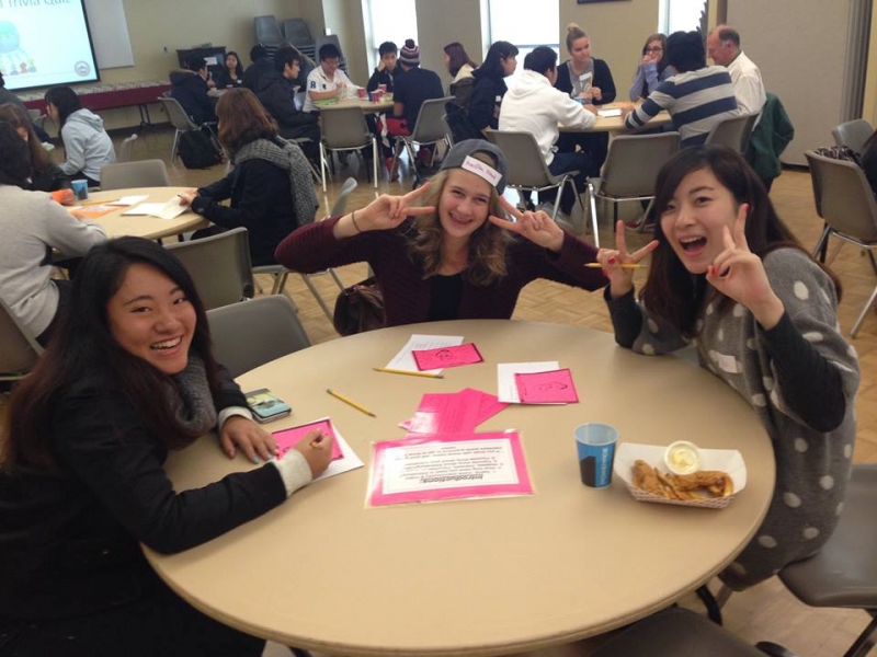 3 students at a table smiling at the camera
