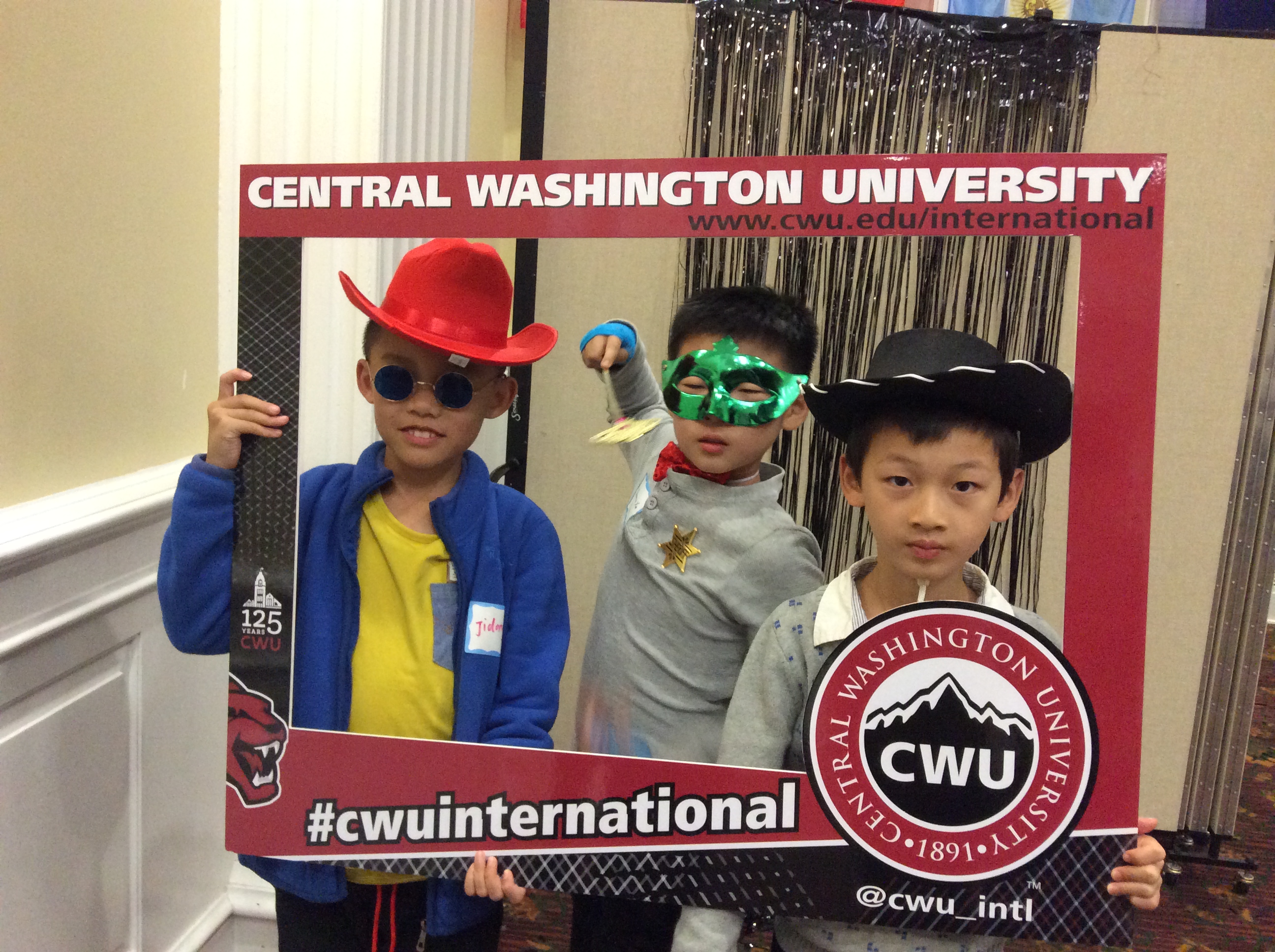 Three kids of our international students pose for a picture dressed in costumes at our Welcome Dinner.