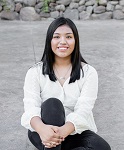 Abby Limonteco-Tlatelpa smiling in a photo. She is sitting on the ground