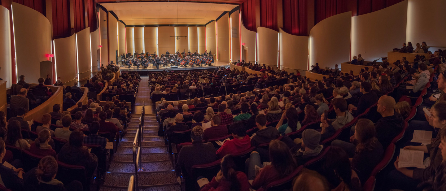 Image from the rear of the concert hall over the audience while orchestra is performing onstage.