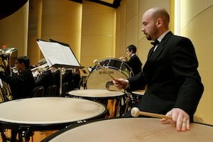 Timpanist muffling the timpani during a wind ensemble performance.