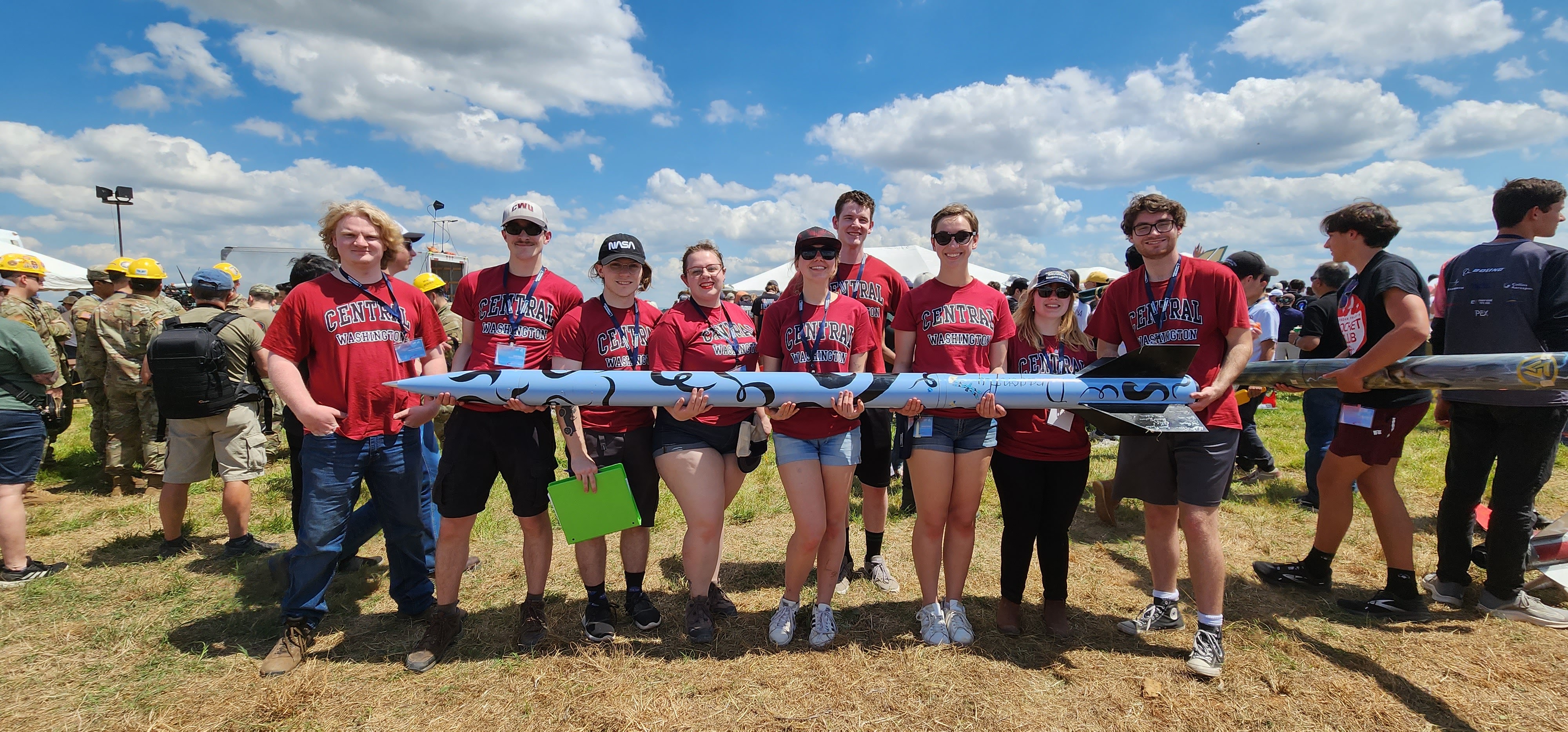 CWU students holding a large rocket outside.