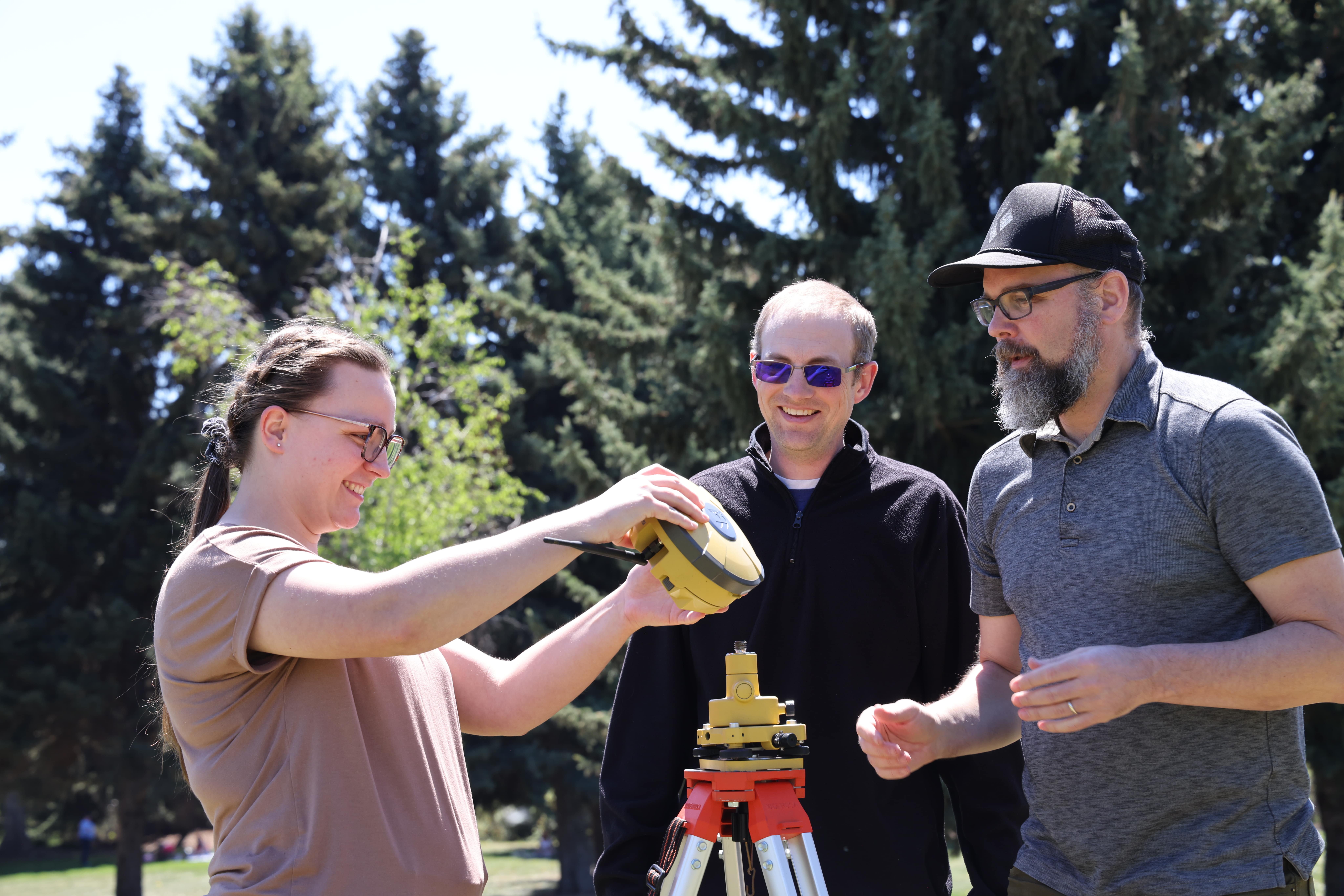 Students and professor outdoors using equipment