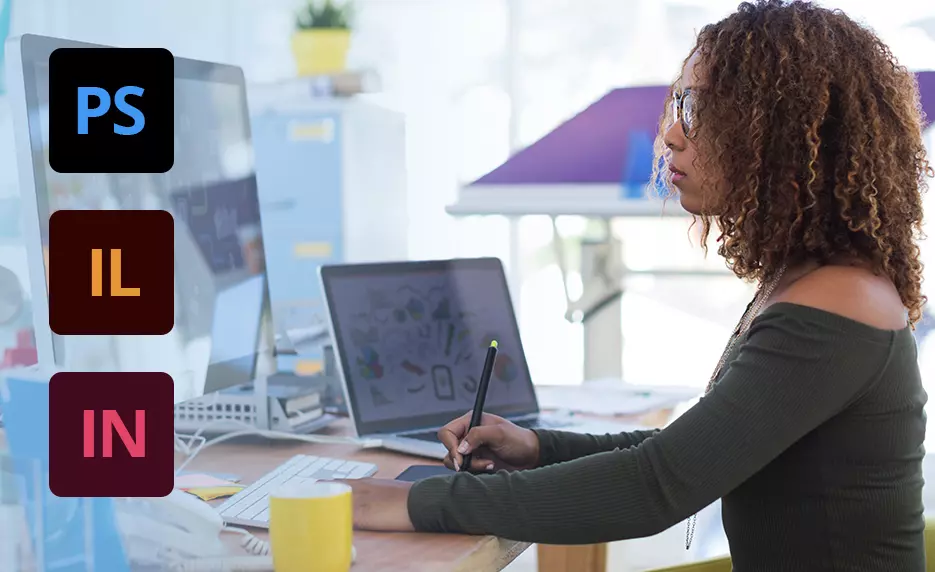 A women working at a desk using a computer and a laptop