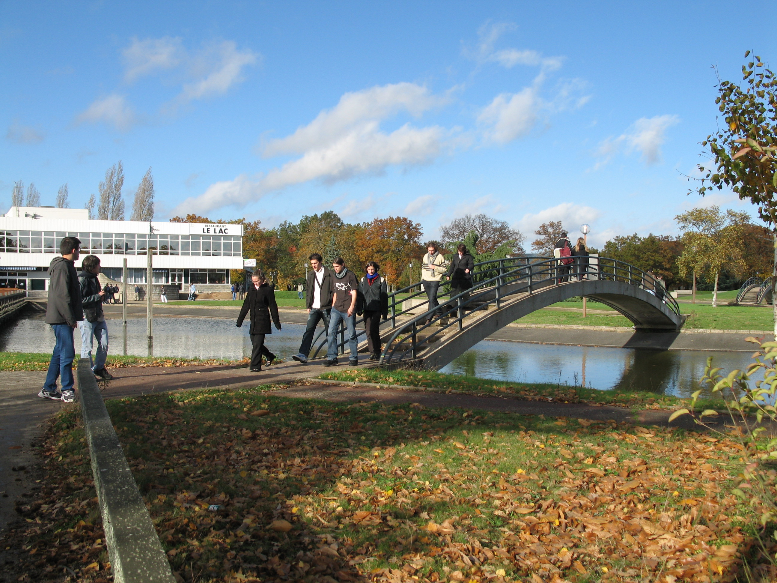 Students Walking Across Bridge Over Pond on University Campus