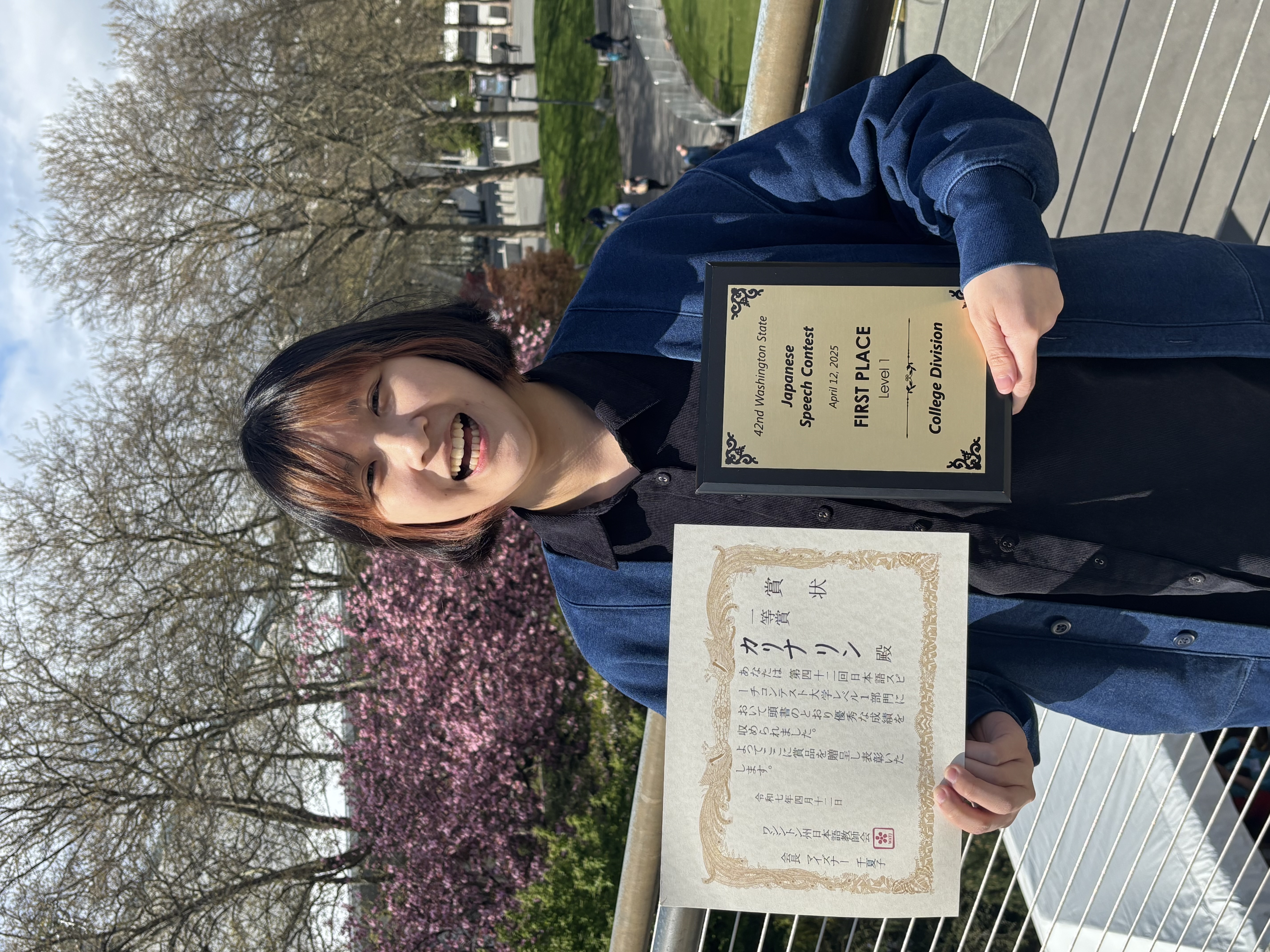 Calina Lin holds the Japanese Speech Contest First Place Award and smiles