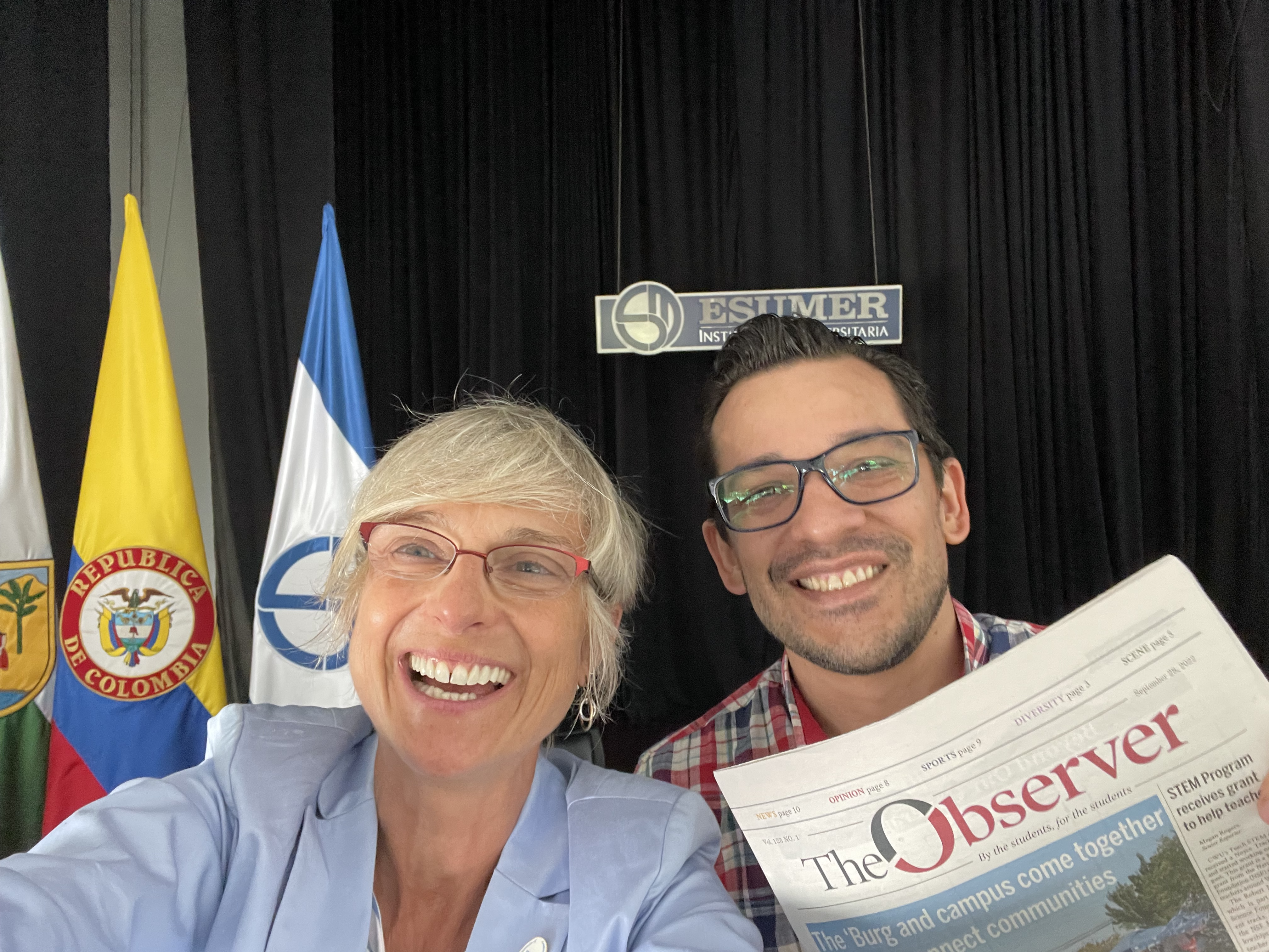 Stella smiling in a selfie with another person who is holding a "The Observer" newspaper.
