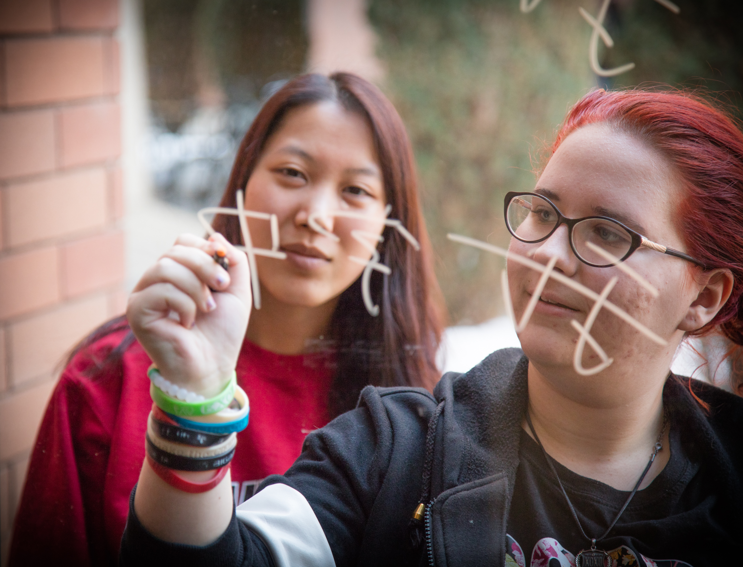 two students practicing writing Japanese