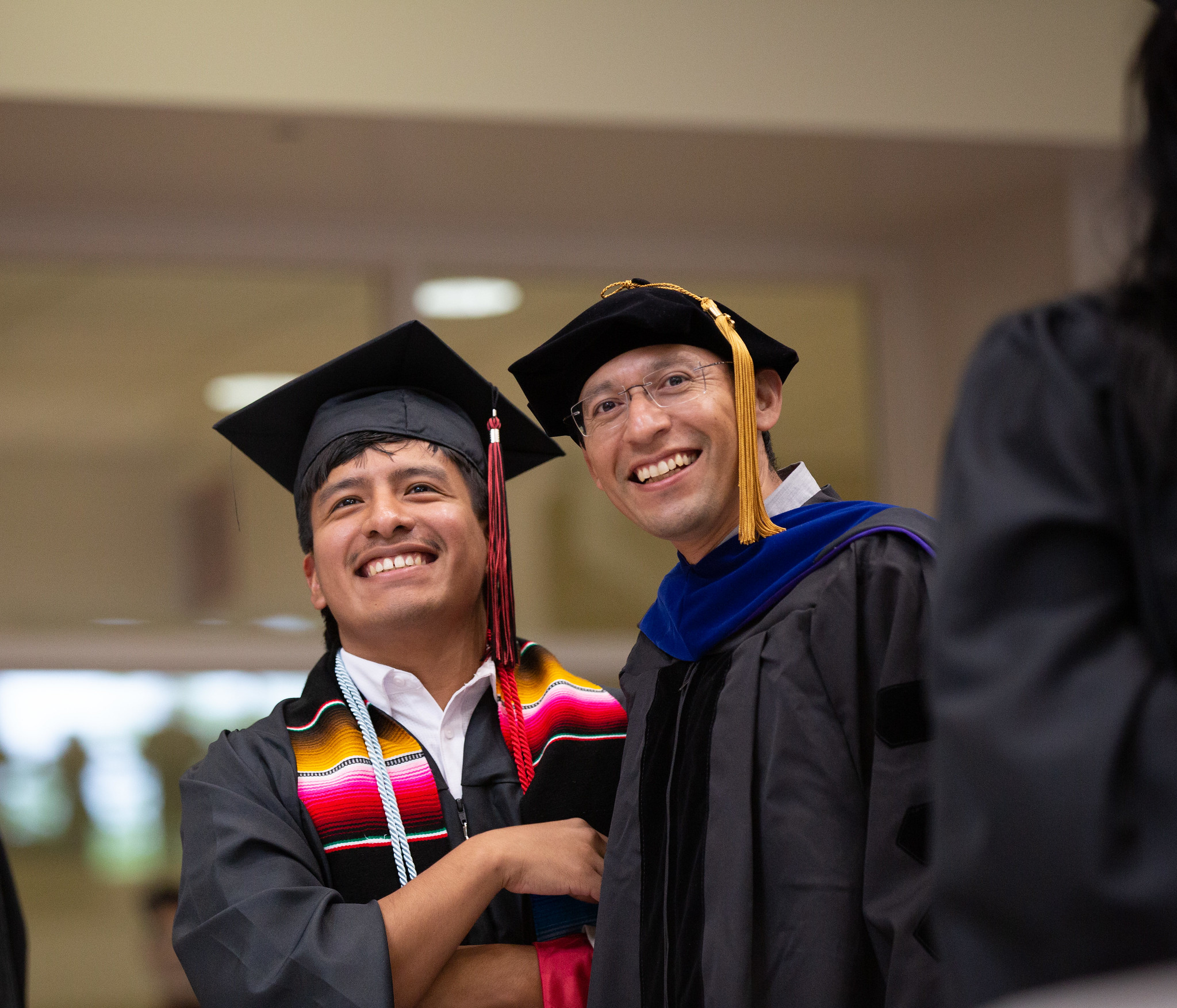 Student standing with his professor at hooding ceremony, smiling ad happy