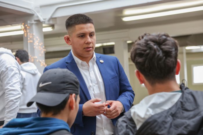 Alvaro "Gonzo" Gonzales speaking with two other people facing away from the camera.