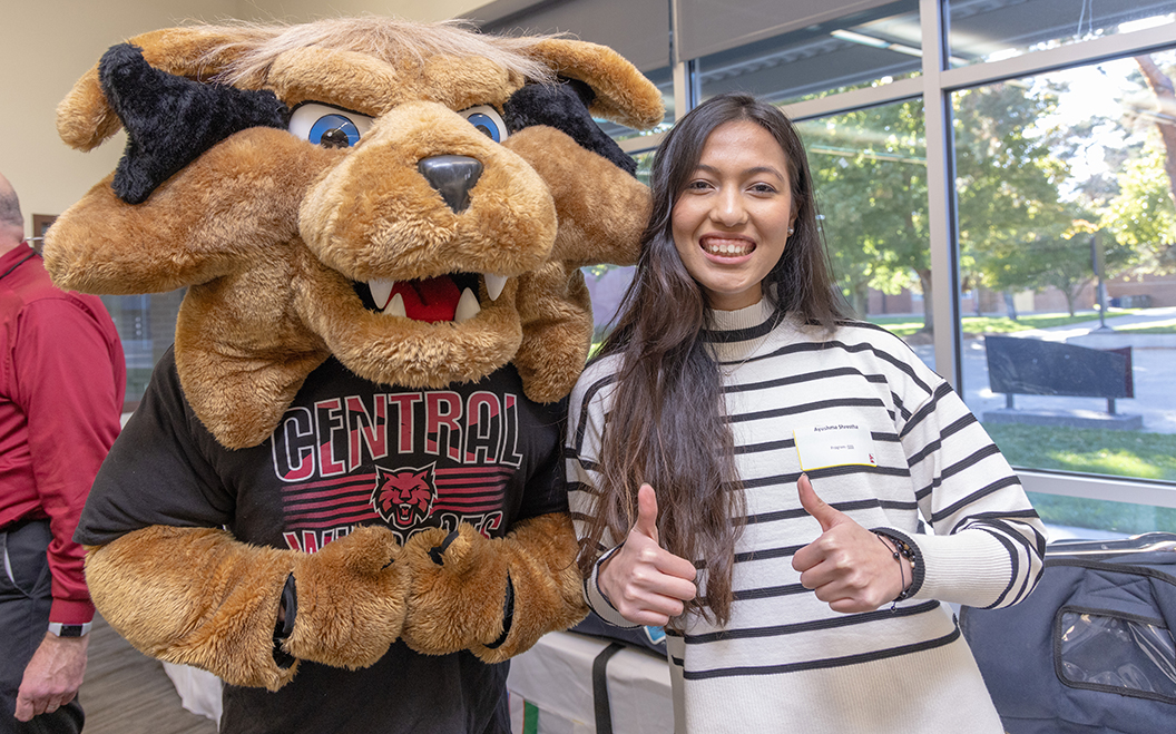 An international student stands with Wellington Wildcat