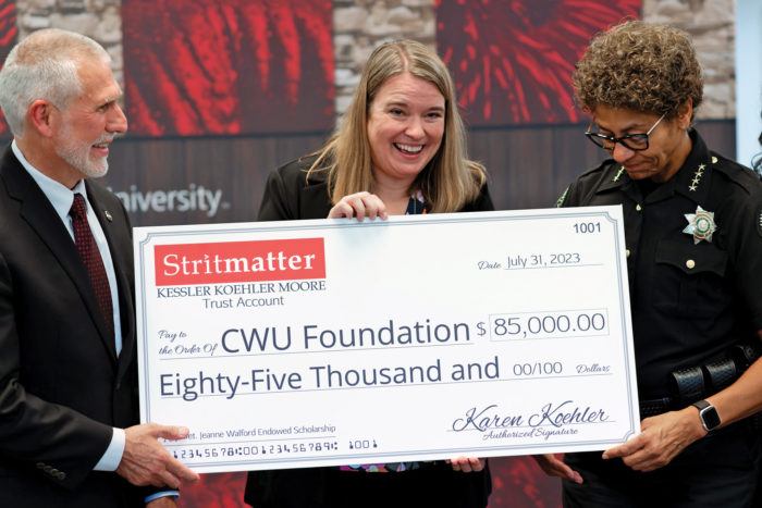 Jeanne Walford receiving a check for 85,000 dollars, accompanied by CWU President Jim Wohlpart and another person.