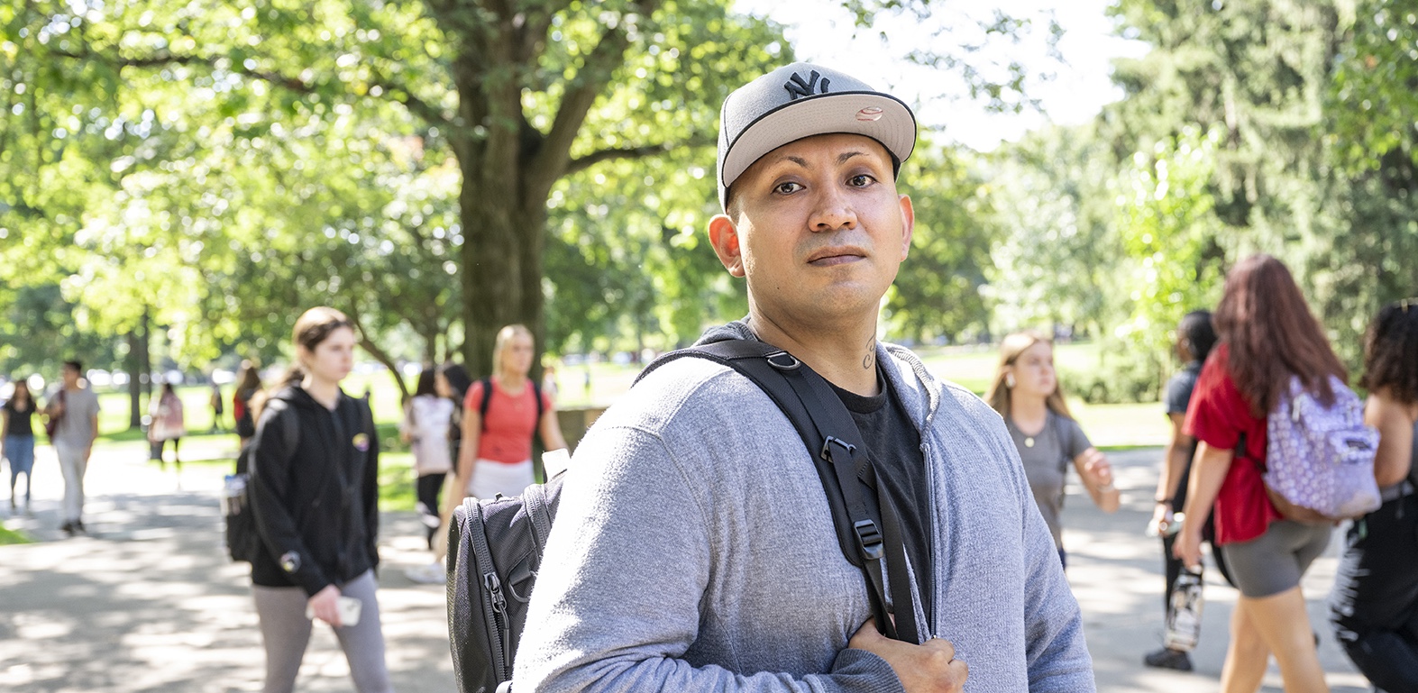 Luis Moreno wearing a backpack with students in the background.