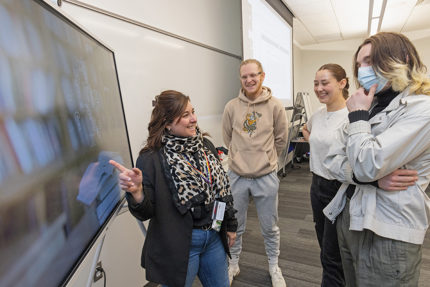 Photo of Andrea Herrera-Dulcet pointing at a screen, much to the amusement of observing students.