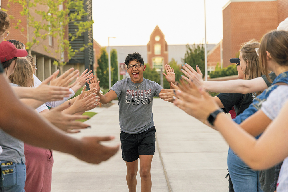 A student gives high-fives to his peers in front of Black Hall
