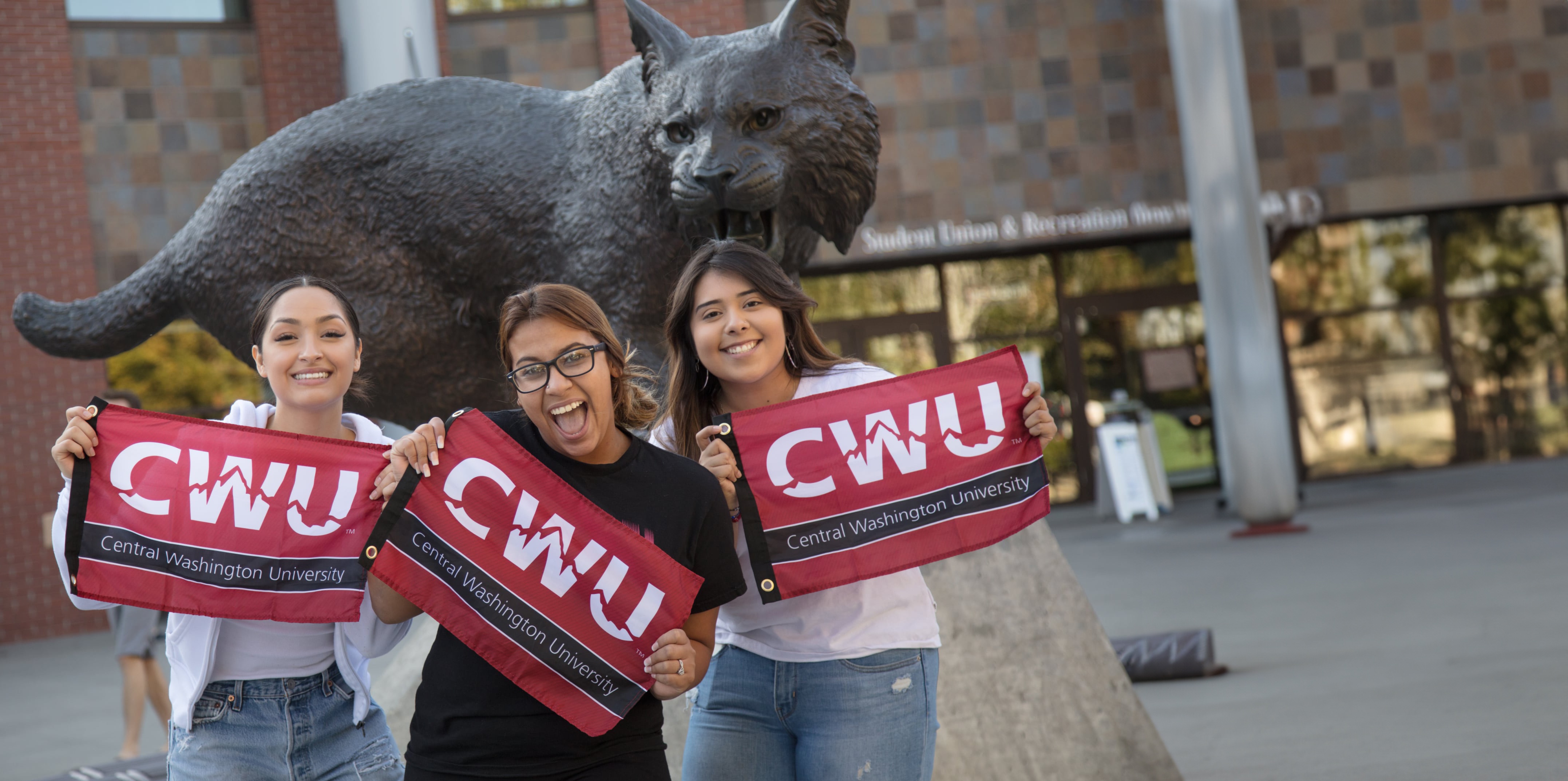 Students standing outside the SURC with CWU flags