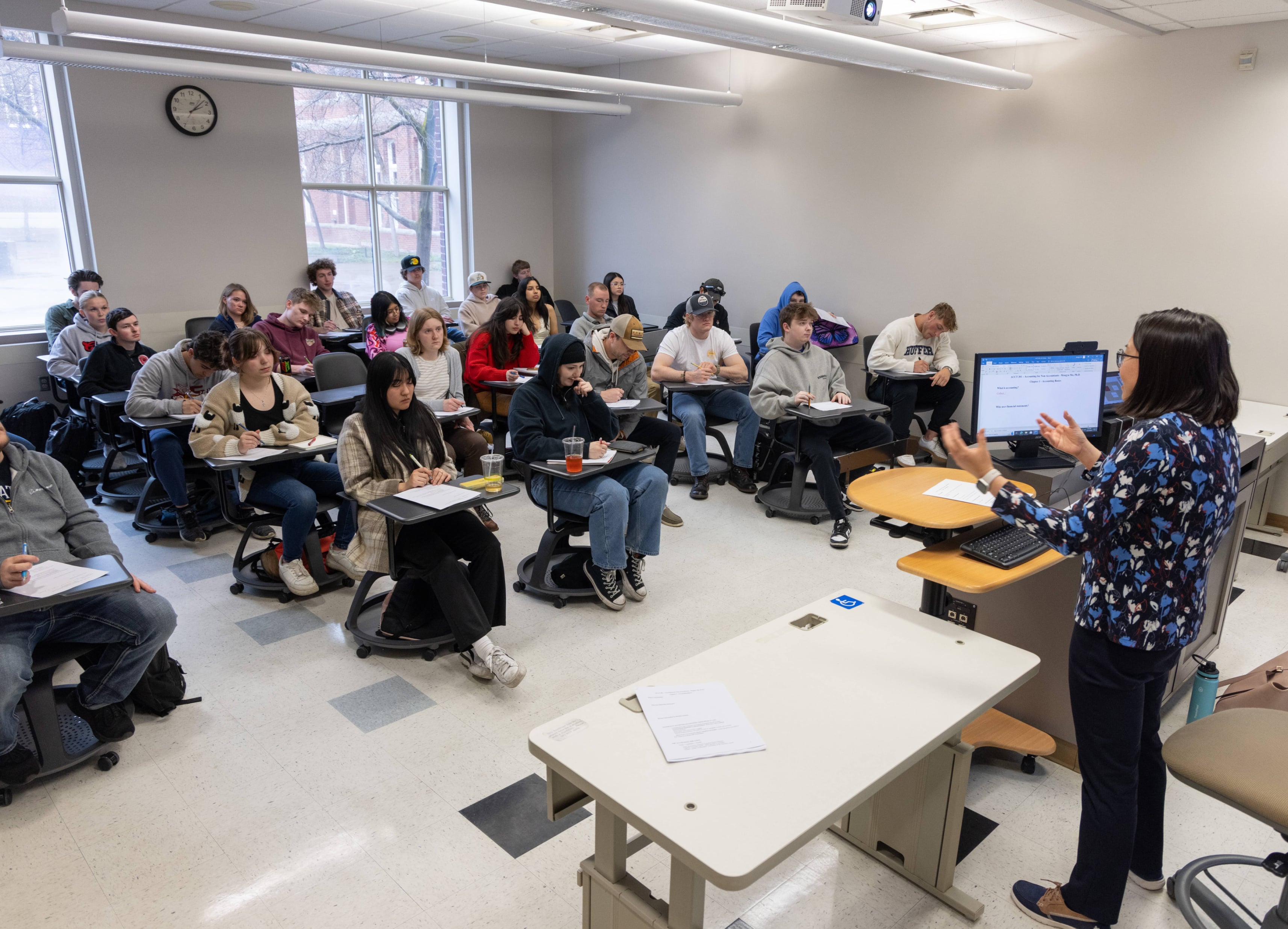Students sitting in a lecture, full classroom shot with professor up front