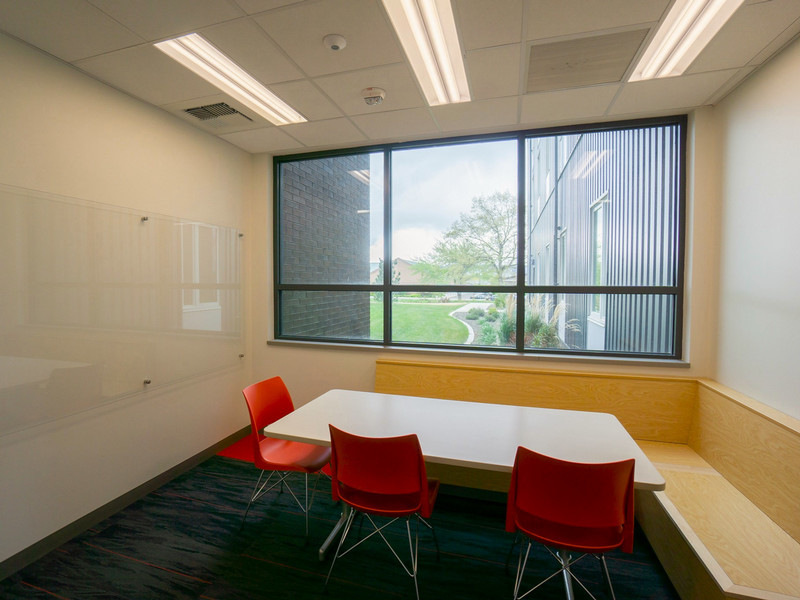 Study nook with white board, table, and bench seating by a window