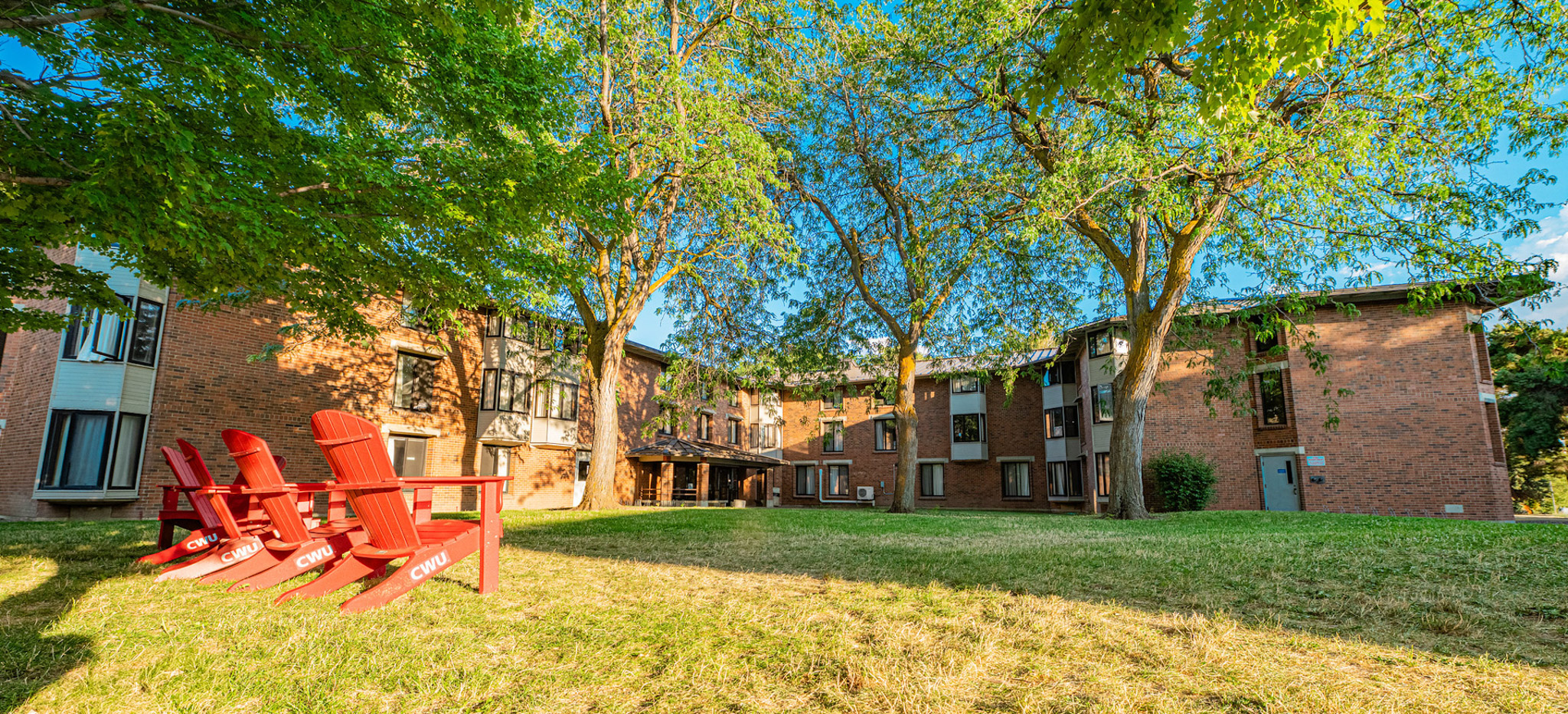Red lawn chairs in front of a residence hall