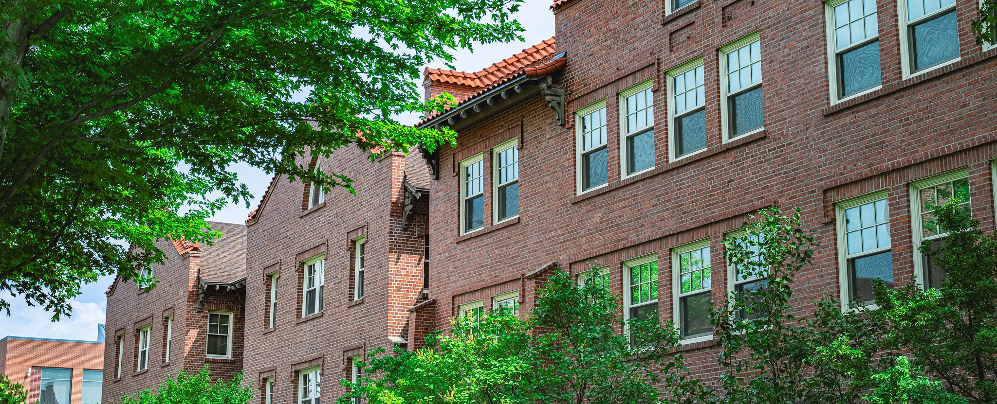 Brick exterior of Kamola Hall in spring with trees blooming