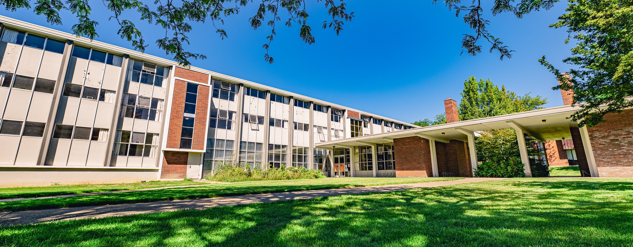 Grey three-story residence hall in the summer